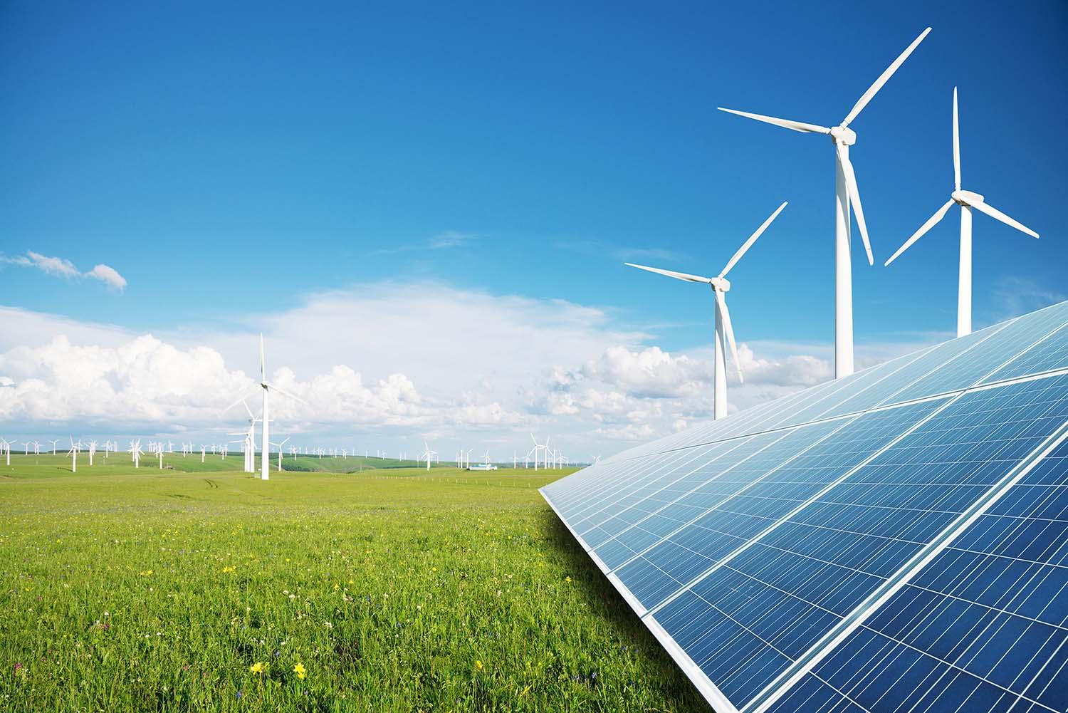 Windmills and solar panels in a green field.